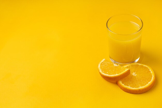 Copo de suco de laranja espremido na hora com frutas em fundo amarelo