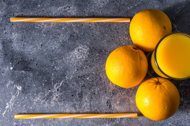 Copo de suco de laranja fresco, frutas maduras e fatias de laranja