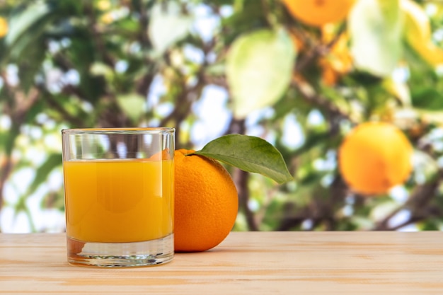 Copo de suco de laranja lá fora na mesa de madeira