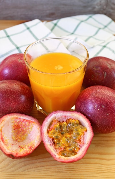 Copo de suco de maracujá fresco com pilha de frutas cortadas e inteiras