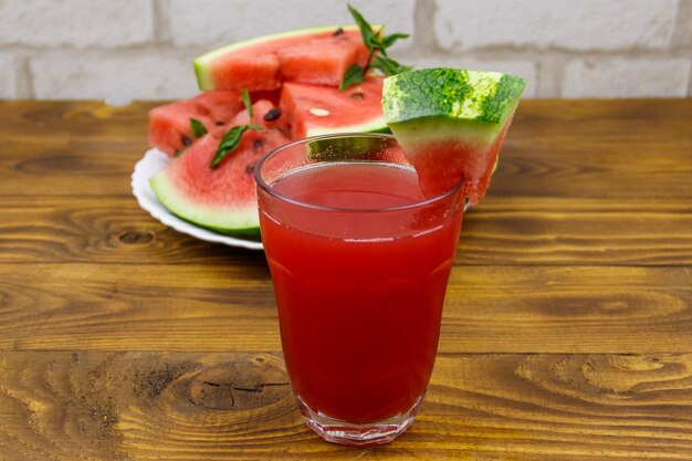 Copo de suco de melancia fresco em uma mesa de madeira