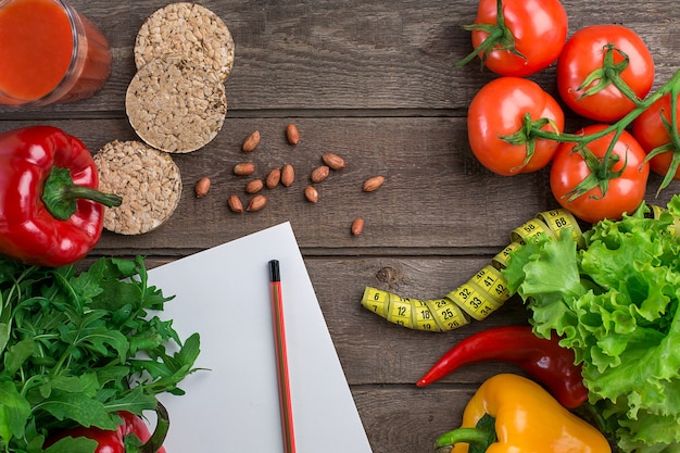 Copo de suco de tomate com legumes e fita métrica na mesa closeup