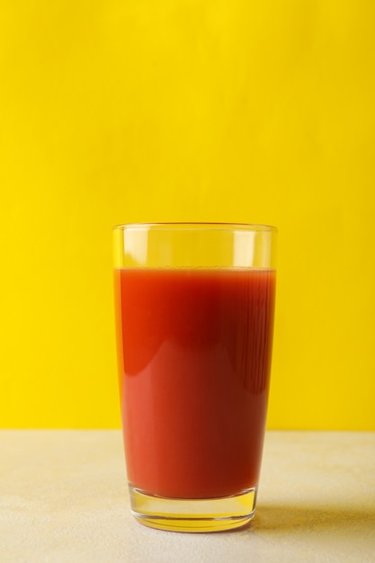 Foto copo de suco de tomate contra amarelo