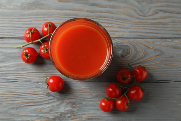 Copo de suco de tomate e tomate na mesa de madeira cinza