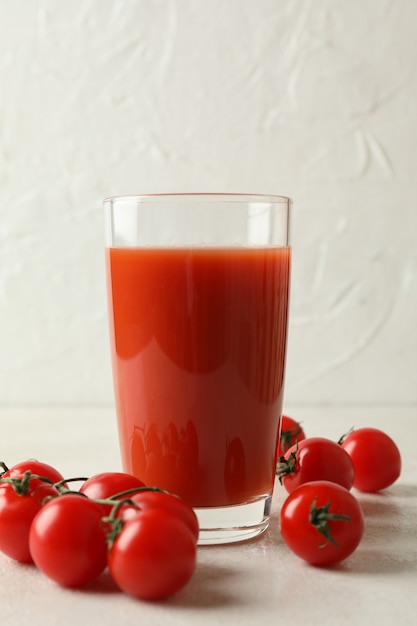 Copo de suco de tomate e tomates em branco texturizado