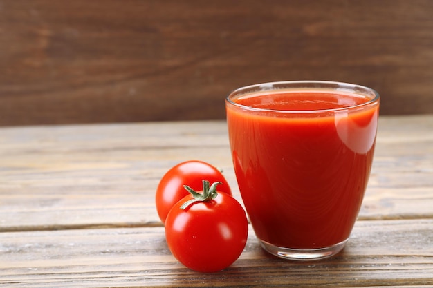 Copo de suco de tomate fresco em fundo de madeira