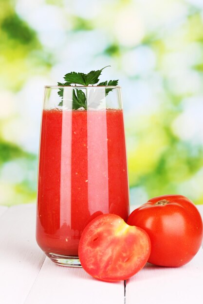 Copo de suco de tomate na mesa de madeira sobre fundo verde