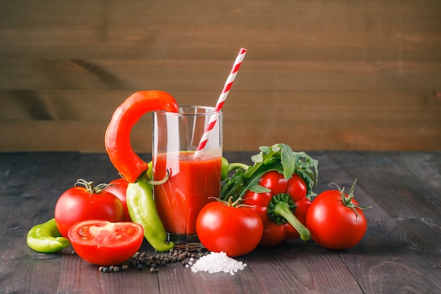 Copo de suco de tomate saboroso e tomates frescos na mesa