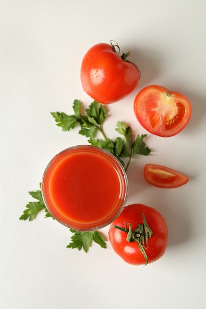 Copo de suco de tomate, tomate e salsa no fundo branco