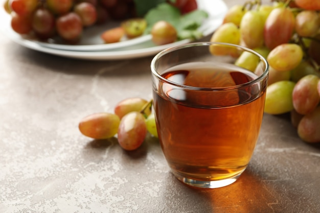 Foto copo de suco e prato com uva em cinza