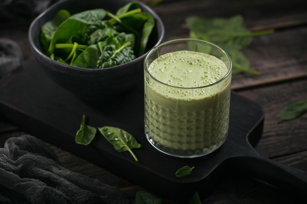 Copo de suco verde saudável caseiro com espinafre fresco em fundo escuro. Alimentos e bebidas, dieta e conceito de alimentação saudável