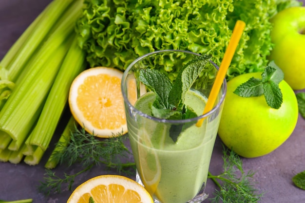 Copo de suco verde saudável com frutas e legumes na mesa