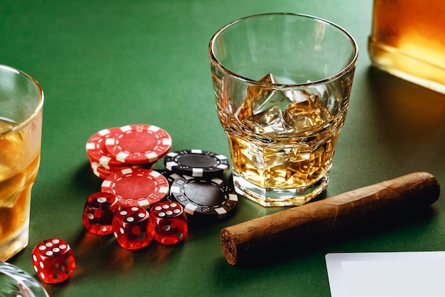 Copo de whisky charuto jogando cartas e fichas no verde