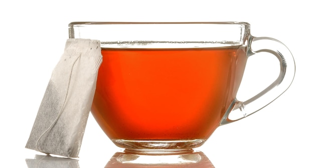 Copo de vidro com chá e saquinho de chá fechado sobre fundo branco isolado