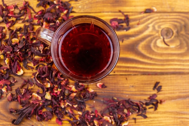 Copo de vidro de roselle de carcade de chá de hibisco vermelho na mesa de madeira