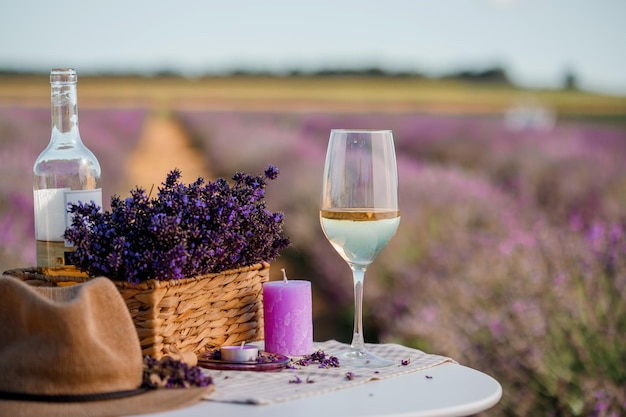 Copo de vinho branco e garrafa em um campo de lavanda em flores Provance Violet no fundo