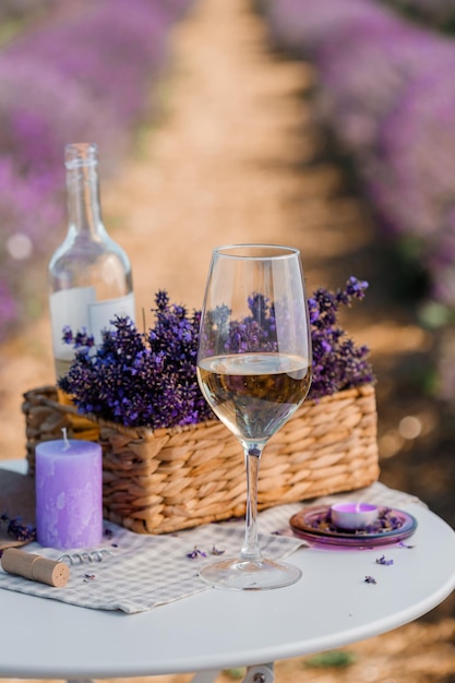 Copo de vinho branco e garrafa em um campo de lavanda em flores Provance Violet no fundo