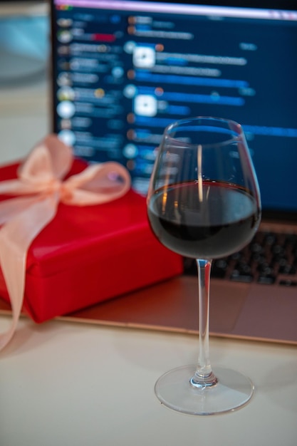 Copo de vinho com caixa de presente na frente do laptop namoro online