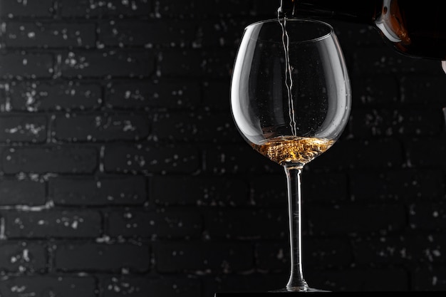 Copo de vinho destacado com derramamento de bebida de álcool no escuro