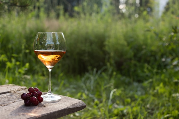 Copo de vinho em uma mesa de madeira em um jardim de verão à noite