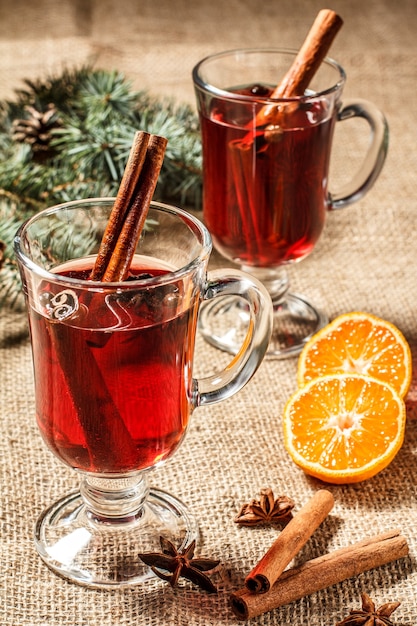 Copo de vinho quente de natal com canela, anis estrelado e cravo no saco com fatias de laranja, galhos de árvores de abeto natural e cones. efeito de tonificação de cor.