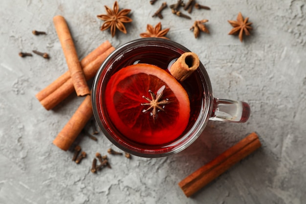 Copo de vinho quente e canela em fundo cinza