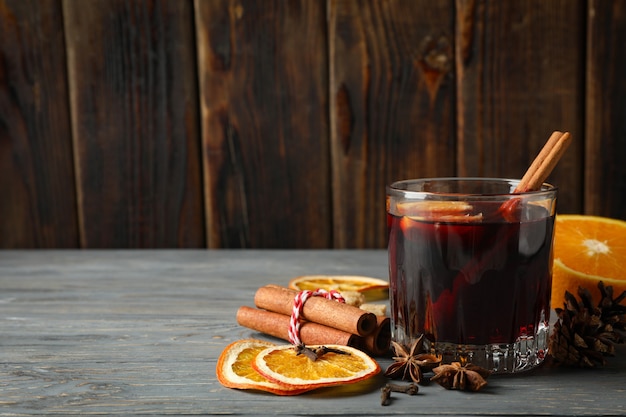 Copo de vinho quente e ingredientes na mesa de madeira cinza