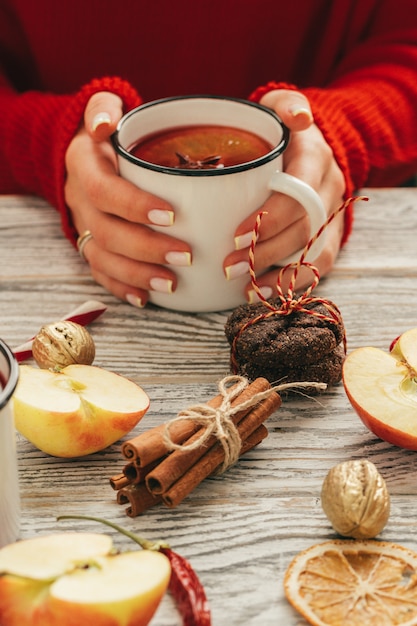 Copo de vinho quente nas mãos da mulher na mesa de superfície de madeira