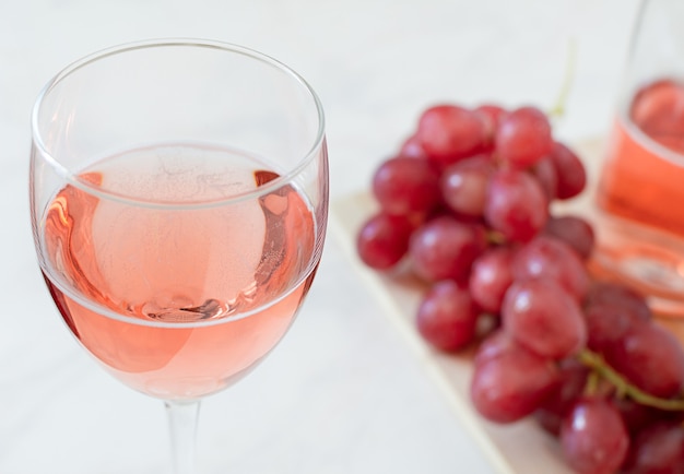 Copo de vinho rosé, uvas e garrafa.