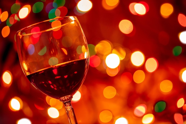 Copo de vinho tinto contra fundo de bokeh de luzes de natal