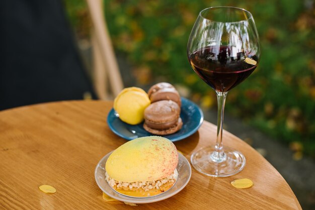 Copo de vinho tinto e biscoitos na mesa ao ar livre no terraço com queda de folhagem amarela. Conceito de clima de outono