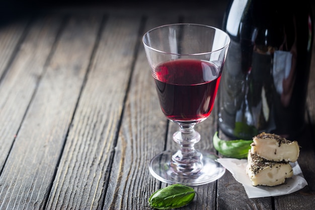 Foto copo de vinho tinto e uma garrafa em fundo escuro de madeira