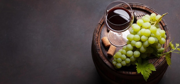 Copo de vinho tinto e uva branca no barril velho