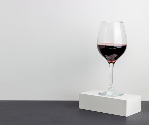 Copo de vinho tinto em uma mesa branca. minimalismo.