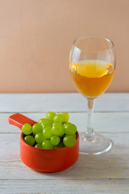 Copo de vinho, uvas verdes no prato na mesa.