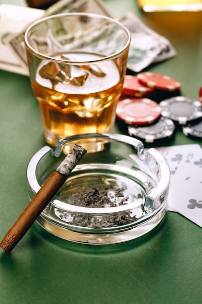 Copo de whisky charuto jogando cartas e fichas na superfície verde