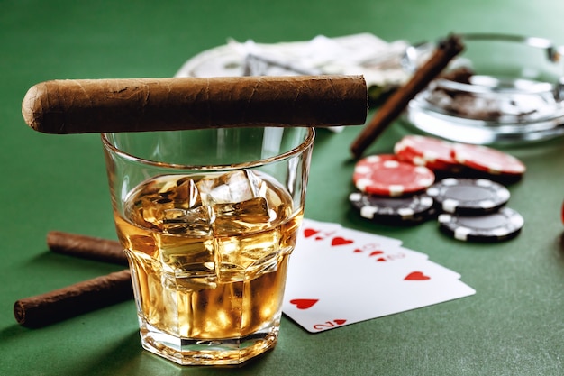 Copo de whisky charuto jogando cartas e fichas no verde