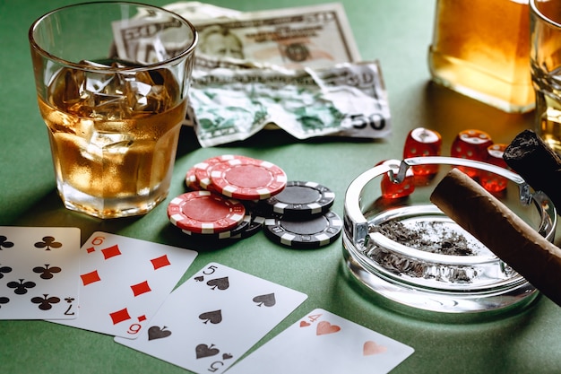 Copo de whisky charuto jogando cartas e fichas no verde