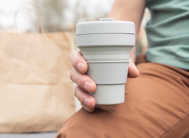 Copo dobrável para café ou chá para viagem. Mão masculina com caneca de silicone sustentável. Vida ecológica.