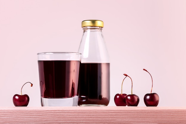 Copo e garrafa com suco de cereja, cerejas na mesa. bebida de dieta saudável.