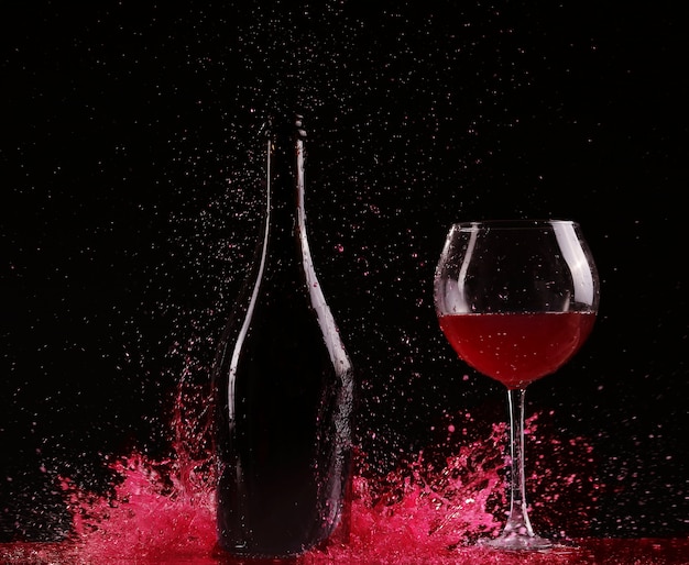 Copo e garrafa de vinho tinto splash em preto