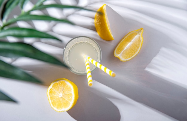 Copo fresco e frio de limonada com limão e brunch de palma em uma mesa clara com fortes sombras matinais