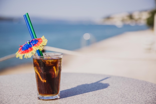 Copo frio de Malibu Cola fica na mesa perto do mar