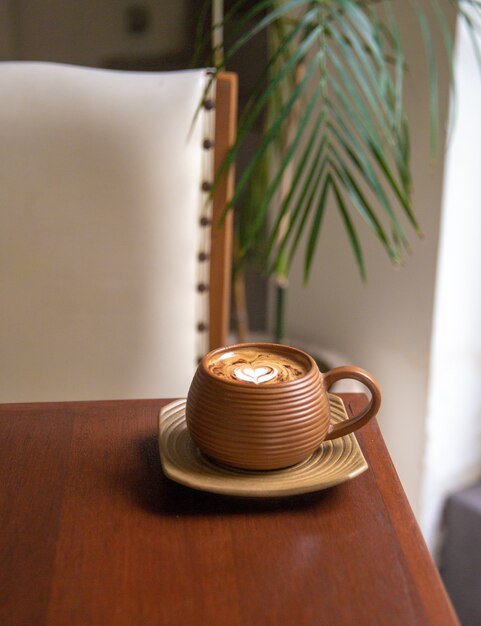 Copo marrom moderno de cappuccino quente no fundo da mesa de madeira