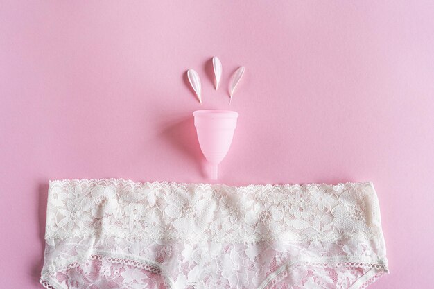 Copo menstrual de silicone Saúde da mulher e higiene alternativa Copo com flor em fundo rosa Alternativas de desperdício zero