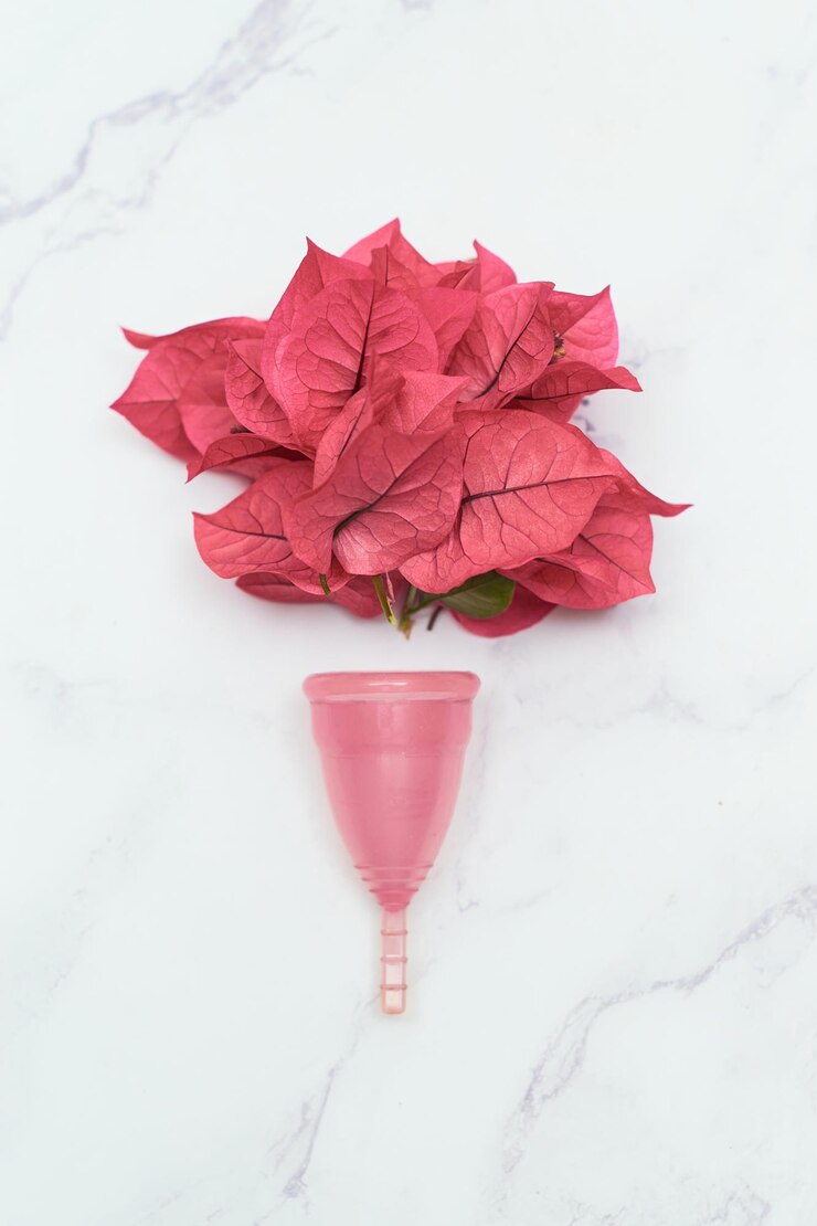 Foto copo menstrual reutilizável com flores de buganvílias em uma mesa de mármore