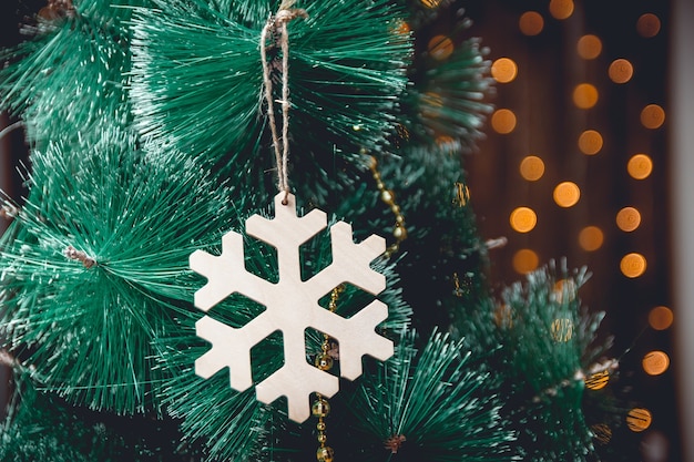 Copo de nieve de decoración de madera de año nuevo en un árbol de navidad