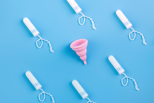Copo ou tampões de escolha de copo menstrual amarelo de silicone para mulheres em um fundo azul ecologicamente correto