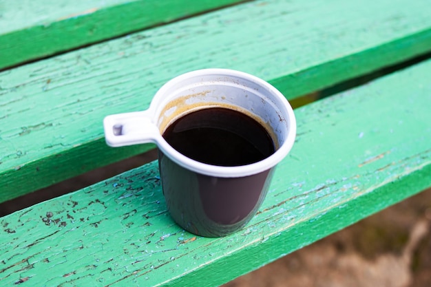 Foto copo plástico com café em um banco de madeira