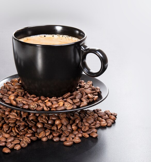 Copo preto com grãos de café em um fundo preto